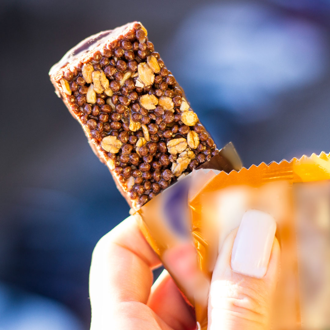 Woman holding nutrition or cereal bar with the wrapper peeled back